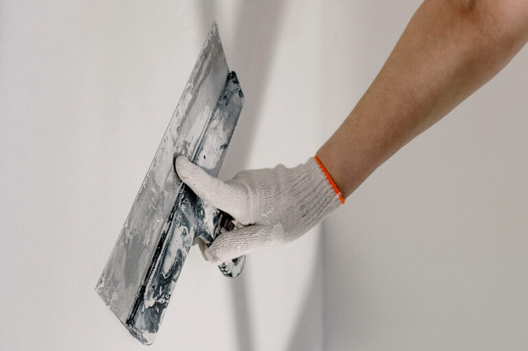 a worker lays down stucco with a spatula
