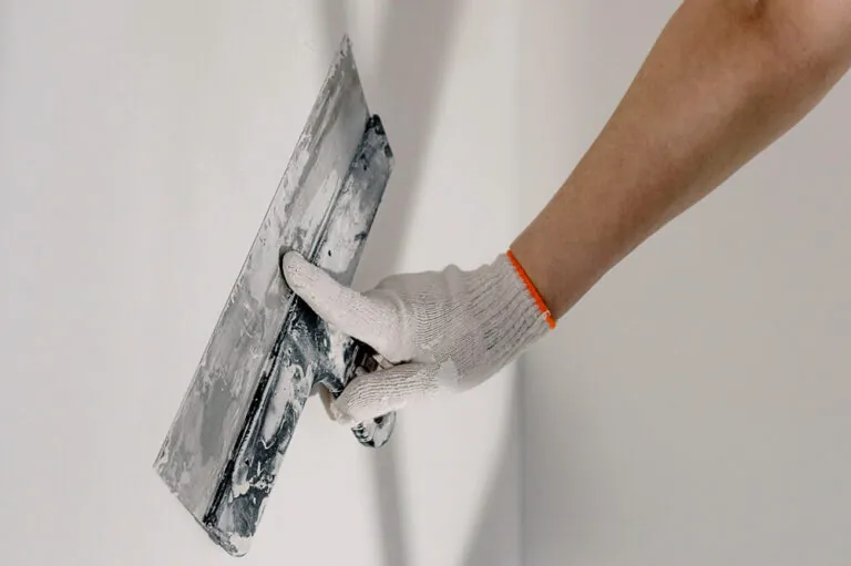 a worker lays down stucco with a spatula