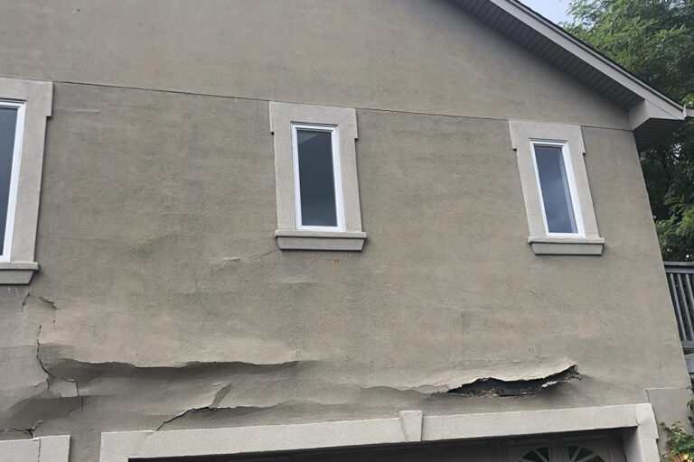 Large sections of loose and delaminating stucco falling from an exterior wall