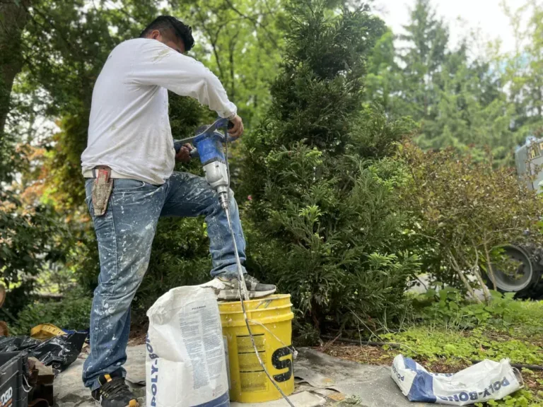 Worker using a power mixer to blend stucco mix in a bucket outdoors, demonstrating precise preparation technique