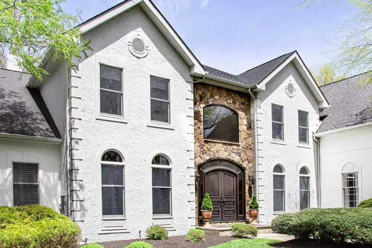 Freshly repaired and painted white stucco exterior with stone entryway on a two-story New Jersey home