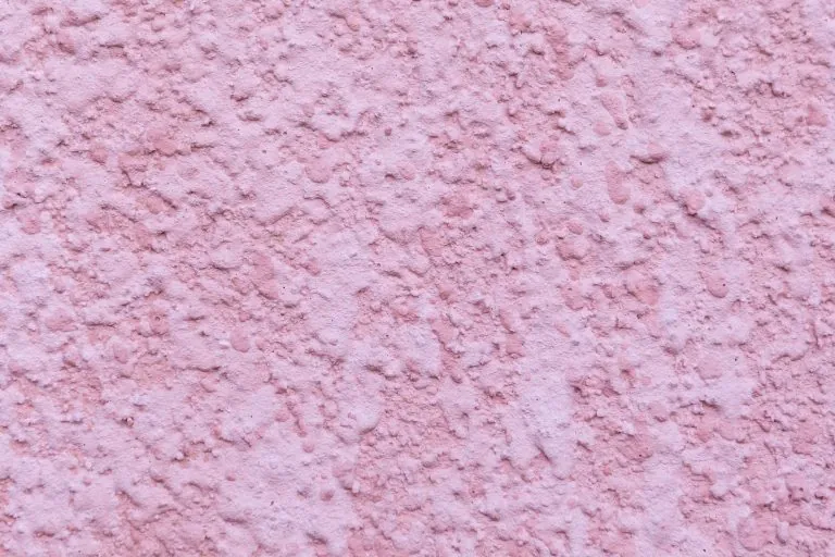 Close-up of rough pink stucco texture showcasing exterior wall finish and color option for home design inspiration