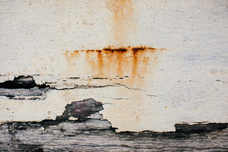 Heavily soiled stucco surface with rust streaks, cracks, and peeling areas showing why regular cleaning matters