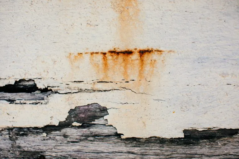 Heavily soiled stucco surface with rust streaks, cracks, and peeling areas showing why regular cleaning matters