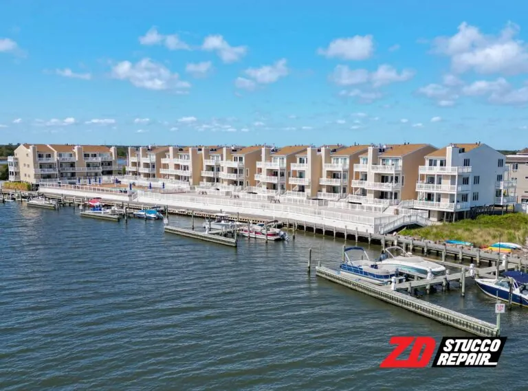 Wide view of restored waterfront condos with fresh stucco, balconies, marina access, and bright blue sky