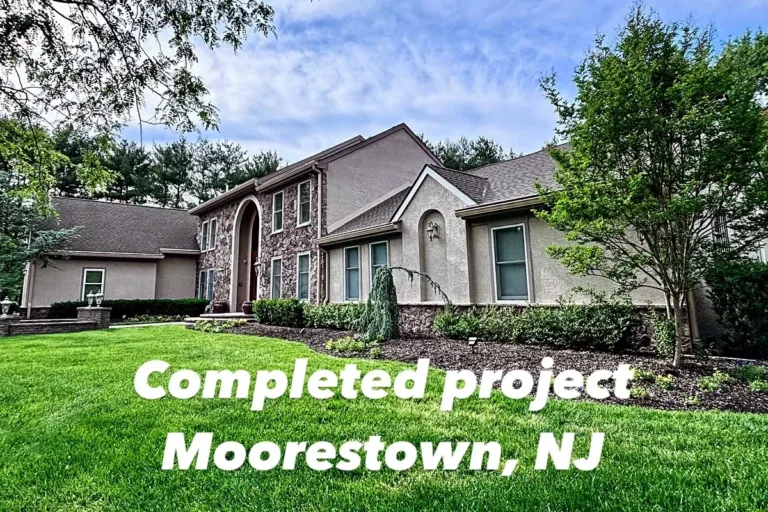 Wide angle view of Moorestown, NJ home after full stucco restoration, showing entire façade, lawn, and landscaping