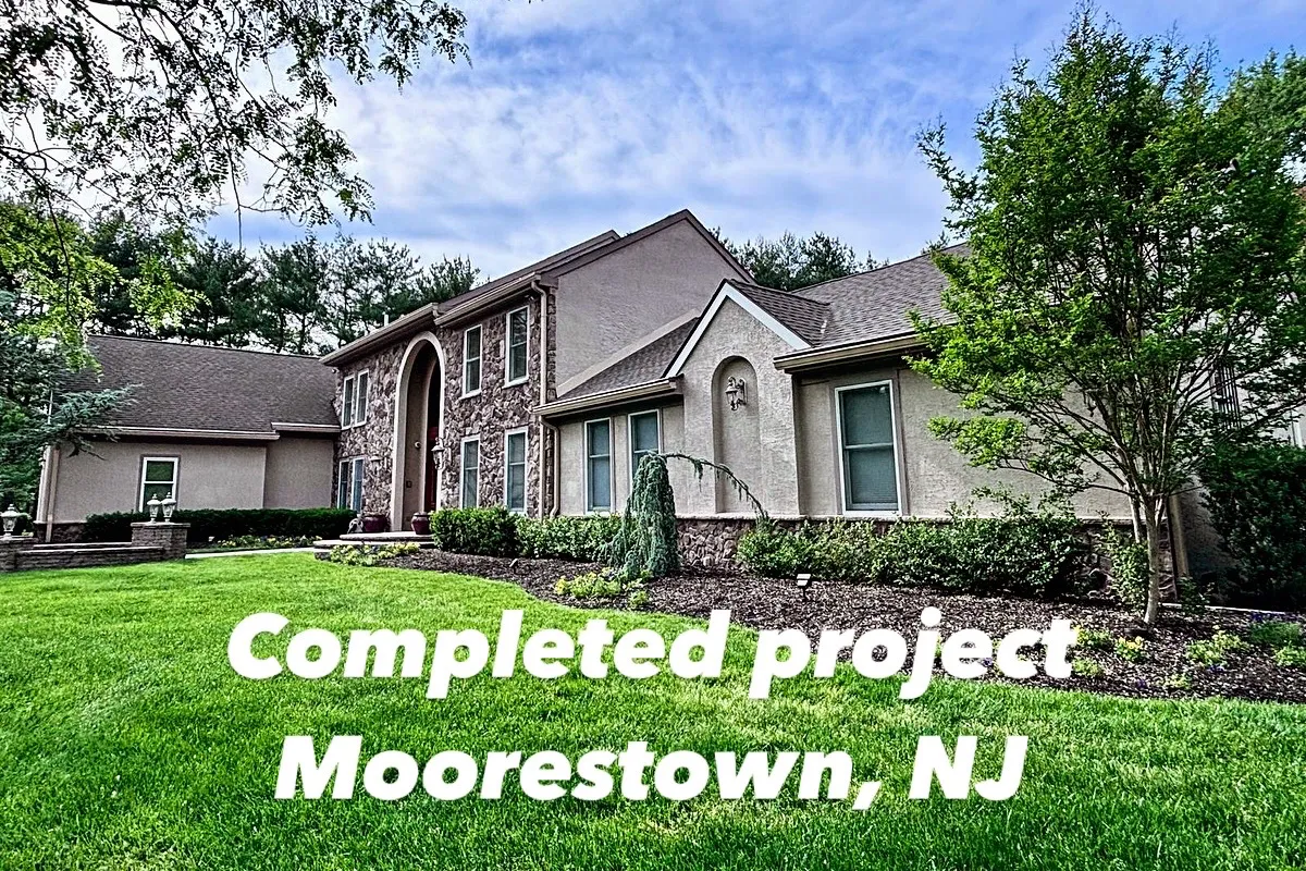 Wide angle view of Moorestown, NJ home after full stucco restoration, showing entire façade, lawn, and landscaping