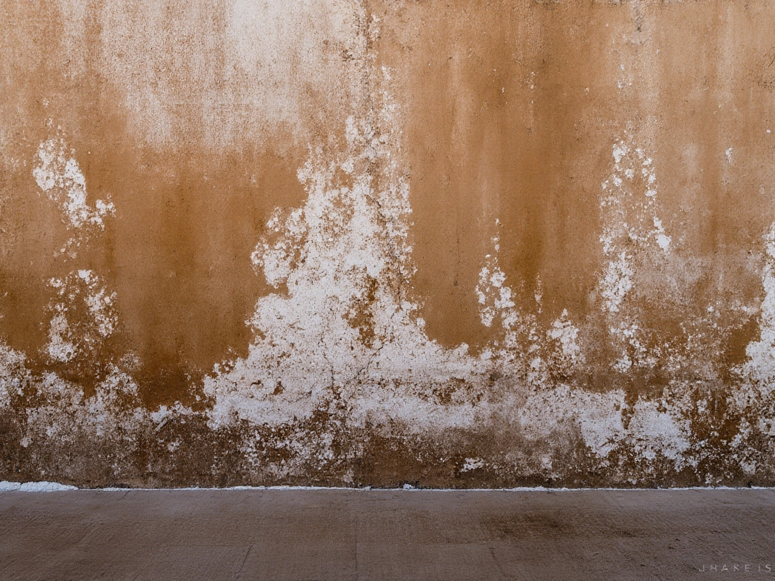 Wide wall section with heavy white salt deposits and discoloration along the lower stucco surface