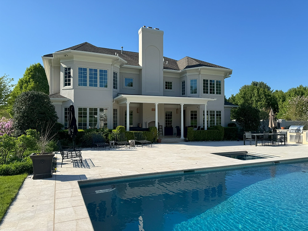 Rear elevation with light stucco walls, covered patio, and pool; work completed by ZD Stucco Repair in Mendham, NJ.