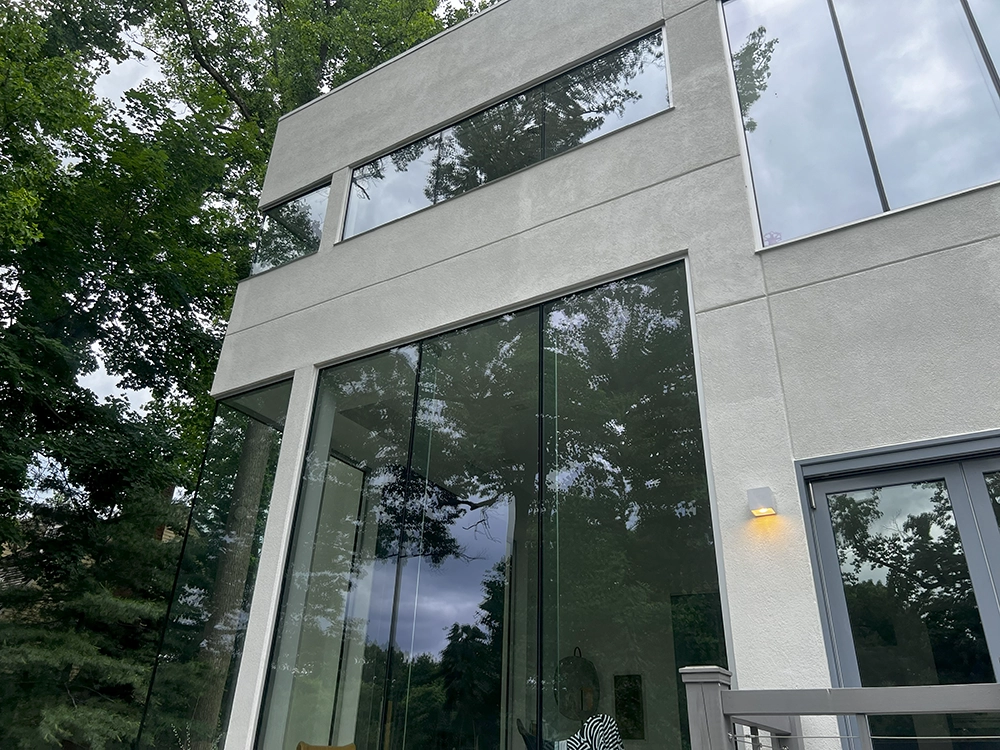 Modern home with smooth light stucco and floor-to-ceiling glass; rear elevation by ZD Stucco Repair in Montclair, NJ.