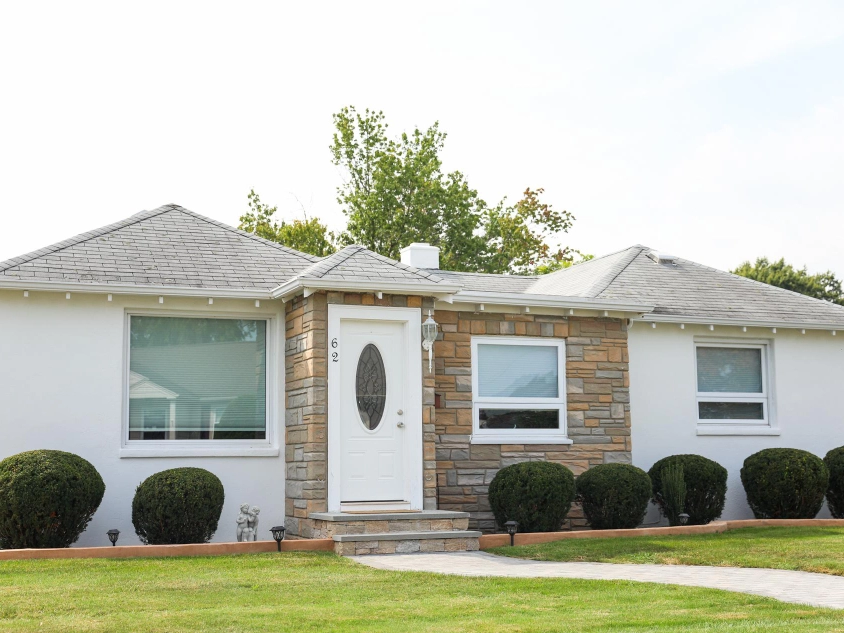 Prices of Stucco Repair and Installation in New Jersey in 2025 3 Front view of a white stucco ranch home with a stone entry, updated windows, and trimmed shrubs in New Jersey