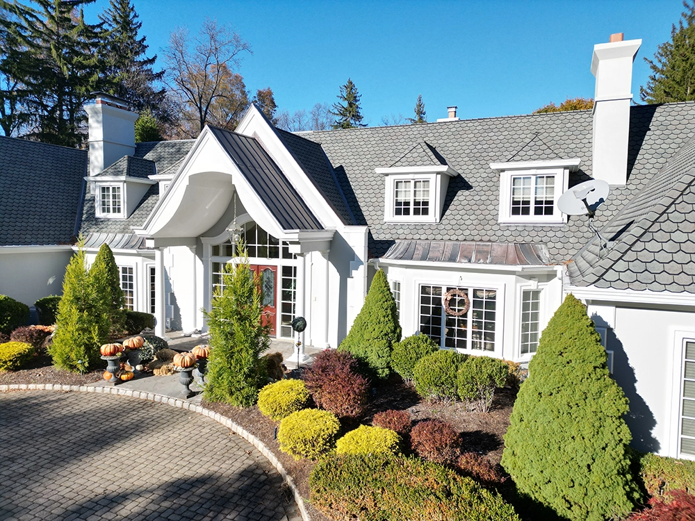 Home 13 Clean light stucco exterior with a curved portico, slate-look roof, and trimmed shrubs; project completed by ZD Stucco Repair in Saddle River, NJ.