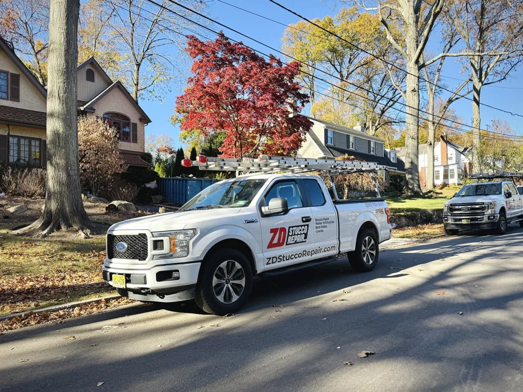 Does Stucco Add Value to Your Home? 7 Company-branded pickup trucks with ladders parked along a tree-lined neighborhood street.