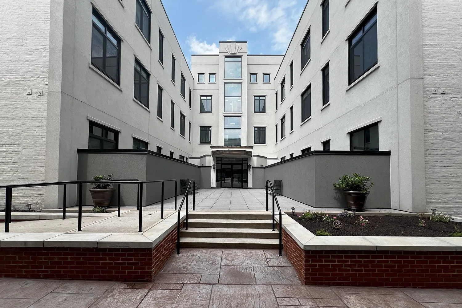Does Stucco Add Value to Your Home? 8 Refinished commercial building courtyard with smooth stucco walls, black railings, and new entry.