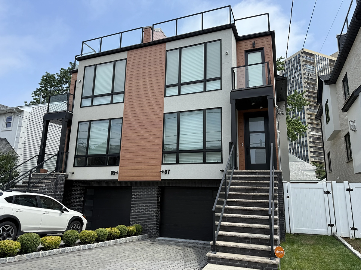 Stucco Repair and Installation in Cliffside Park, NJ 3 Modern duplex in Cliffside Park with smooth light stucco, wood-look vertical panels, black framed windows, and brick base; project by ZD Stucco Repair.