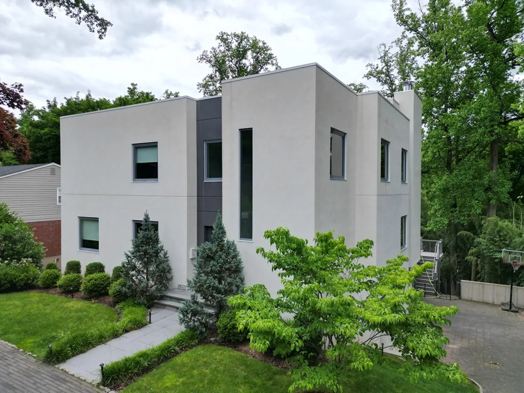 ZD Stucco Repair — Modern Stucco Refinish, Montclair, NJ Modern two-story home with smooth light stucco and narrow windows, landscaped walkway; project by ZD Stucco Repair in Montclair, NJ.