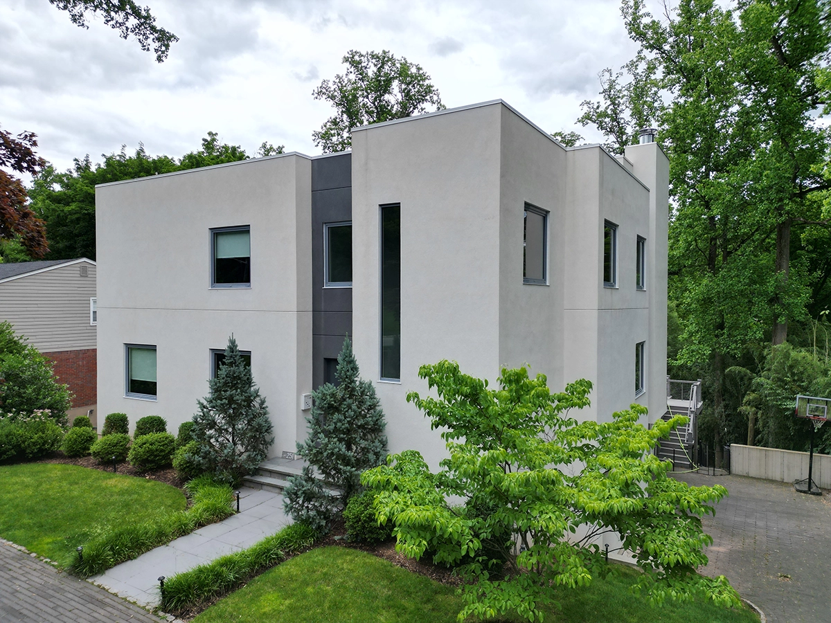 Modern two-story home with smooth light stucco and narrow windows, landscaped walkway; project by ZD Stucco Repair in Montclair, NJ.