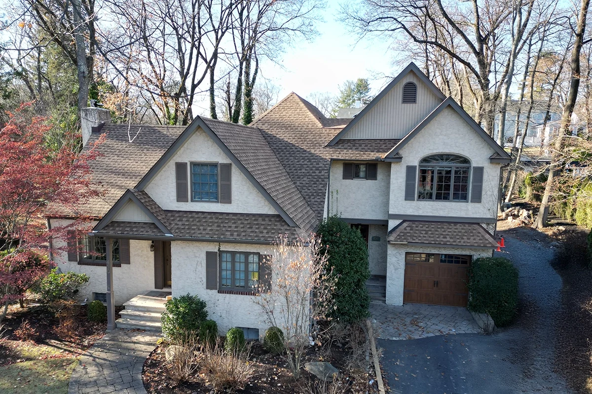 Front aerial of a two-story stucco house in Ridgewood, New Jersey with fresh facade after professional repair