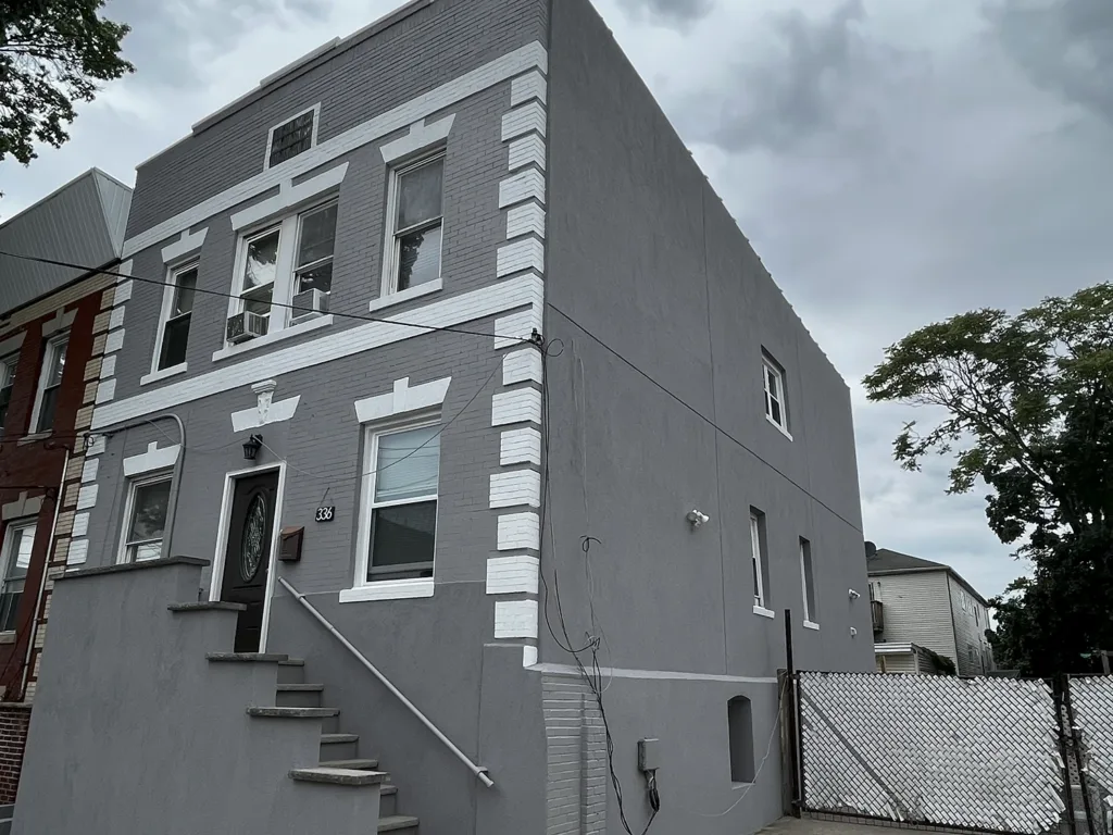 Does Stucco Add Value to Your Home? 6 Urban rowhouse after stucco recoat, gray facade with white decorative trim and updated front steps.
