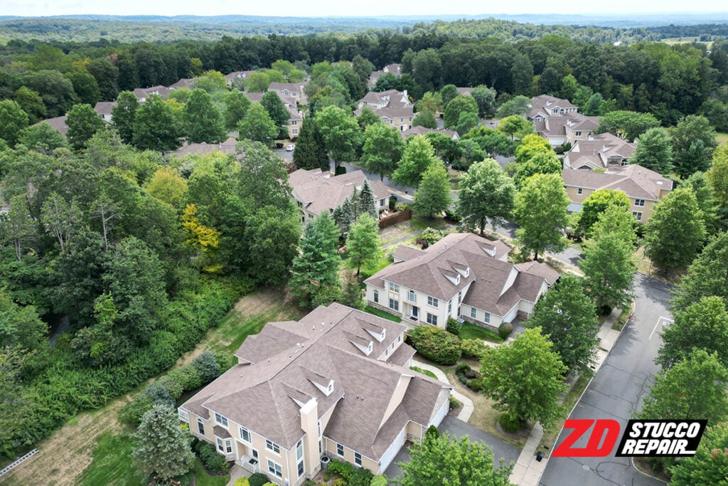 4 Complex Stucco Problems in New Jersey and How ZD Stucco Repair Fixes Them 4 Drone view of Four Seasons at Chester community in NJ showing restored stucco exteriors and roofs surrounded by trees