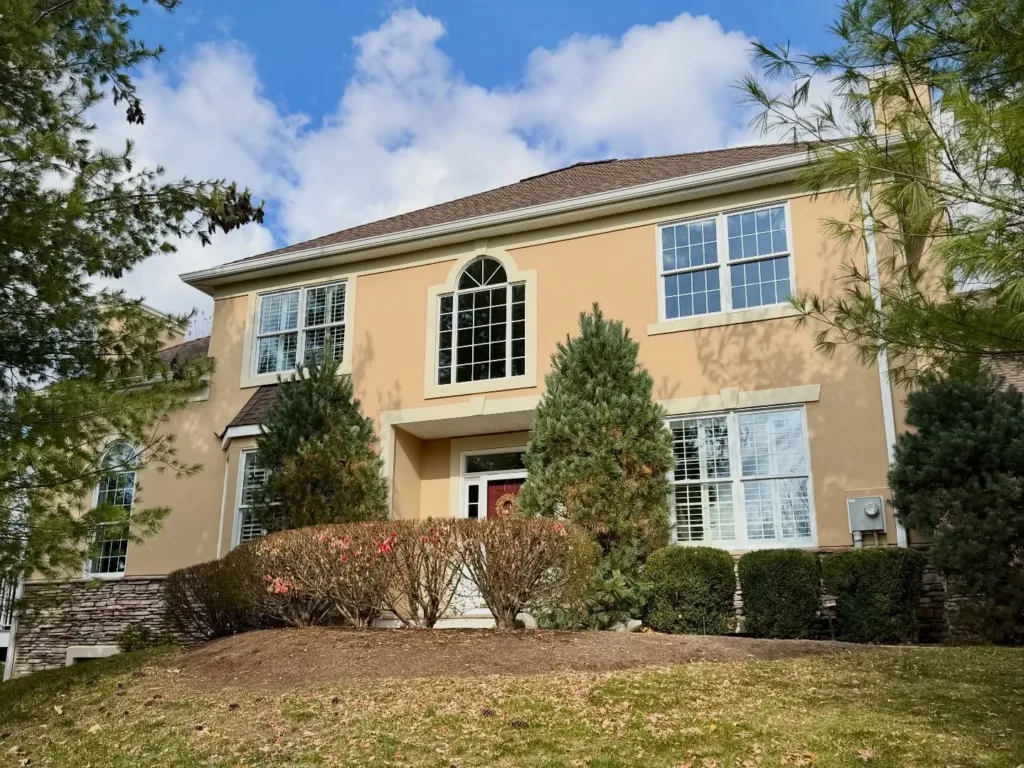 Stucco Repair in NJ: How to Fix Cracks, Damage & Prevent Costly Problems in 2026 5 Front view of a two-story home with clean, smooth stucco facade and white trim