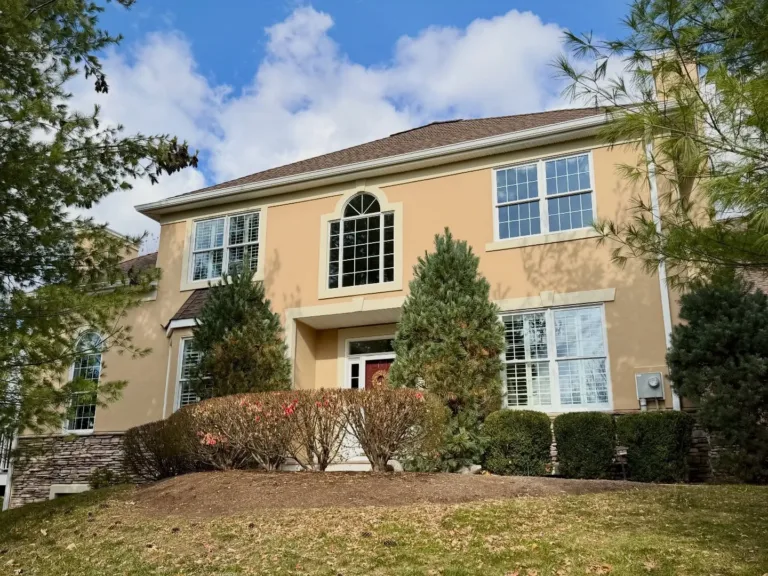 Front view of a two-story home with clean, smooth stucco facade and white trim