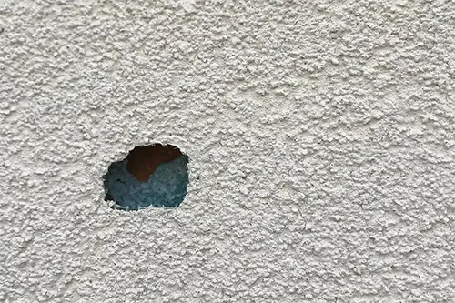 4 Complex Stucco Problems in New Jersey and How ZD Stucco Repair Fixes Them 6 Small round hole in textured stucco or EIFS surface exposing the blue insulation layer underneath