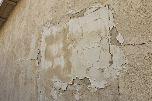 4 Complex Stucco Problems in New Jersey and How ZD Stucco Repair Fixes Them 8 Close-up of cracked and peeling stucco with patched areas separating from the wall surface