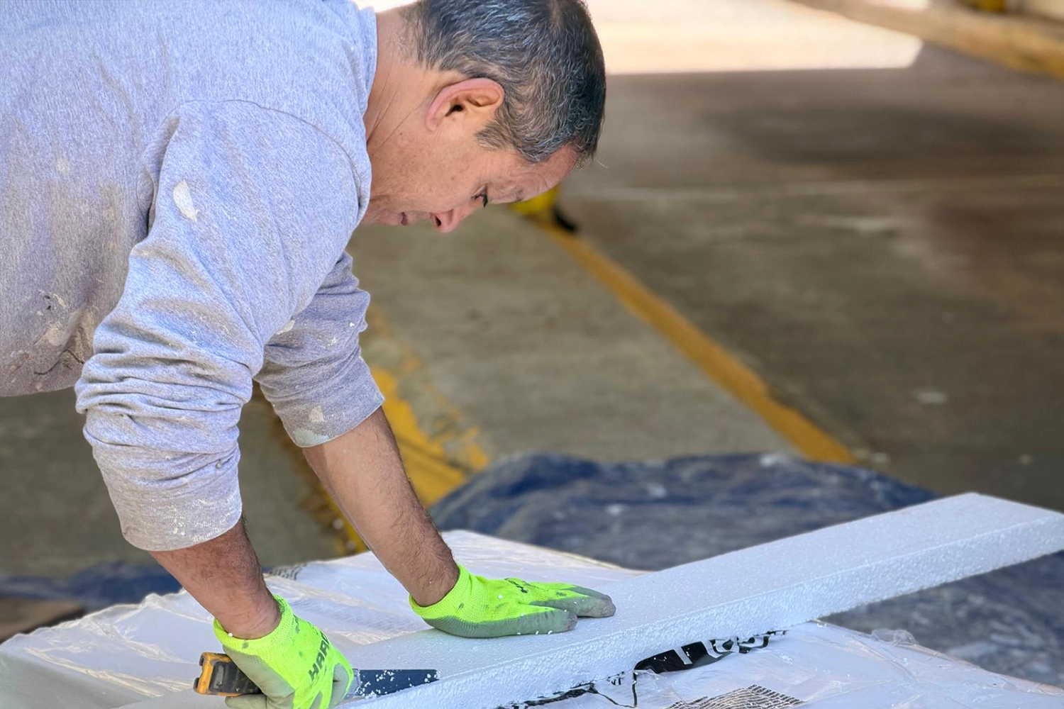 Contractor cuts EIFS foam board for exterior stucco repair and wall restoration work