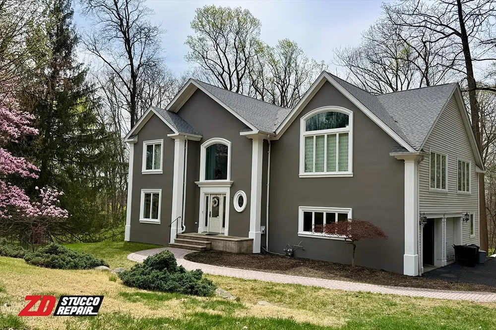Completed Franklin Lakes stucco home with gray exterior finish, white trim, and ZD Stucco Repair branding