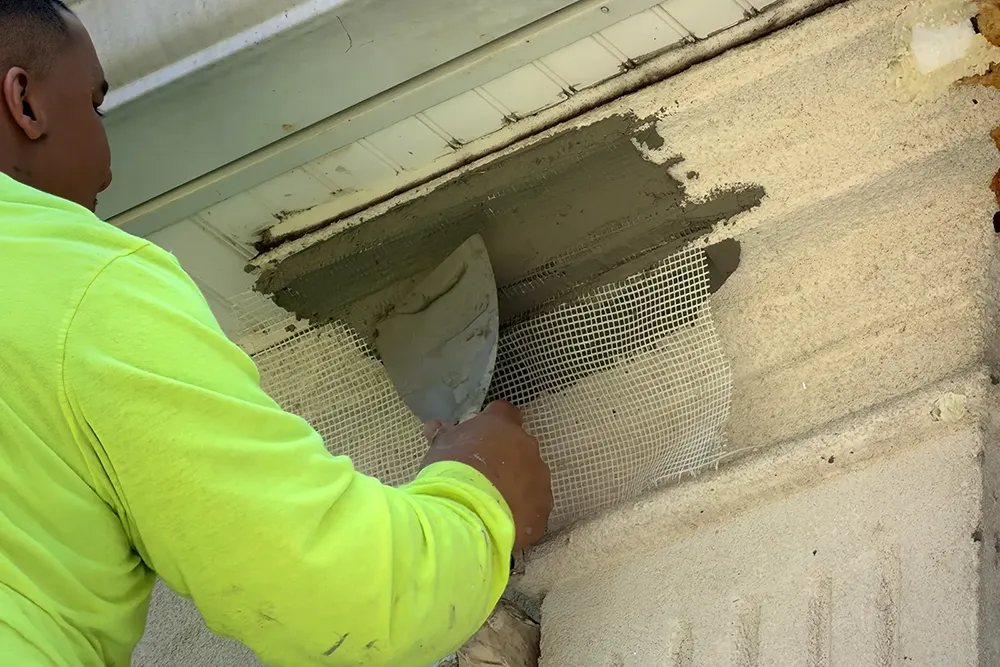 ZD Stucco Repair restores custom-built Franklin Lakes home after 30 years 3 Worker applying base coat over fiberglass mesh during stucco repair on Franklin Lakes home exterior