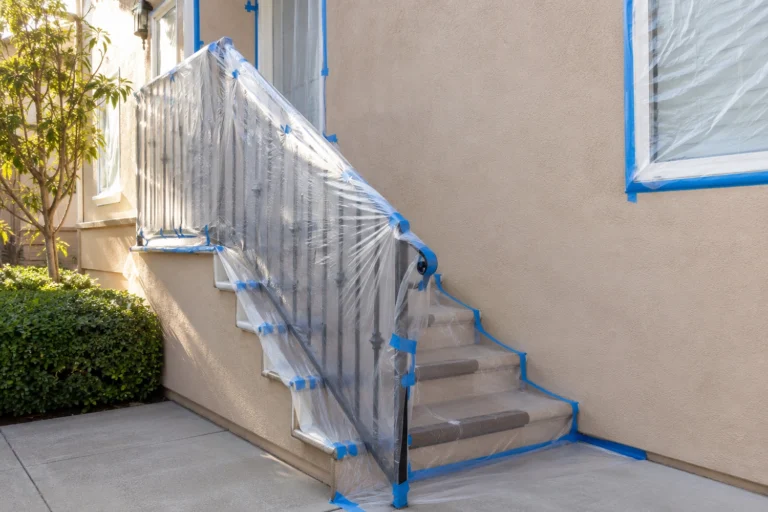 Masked windows, stairs, and railing prepared for clean stucco repair and texture matching in NJ