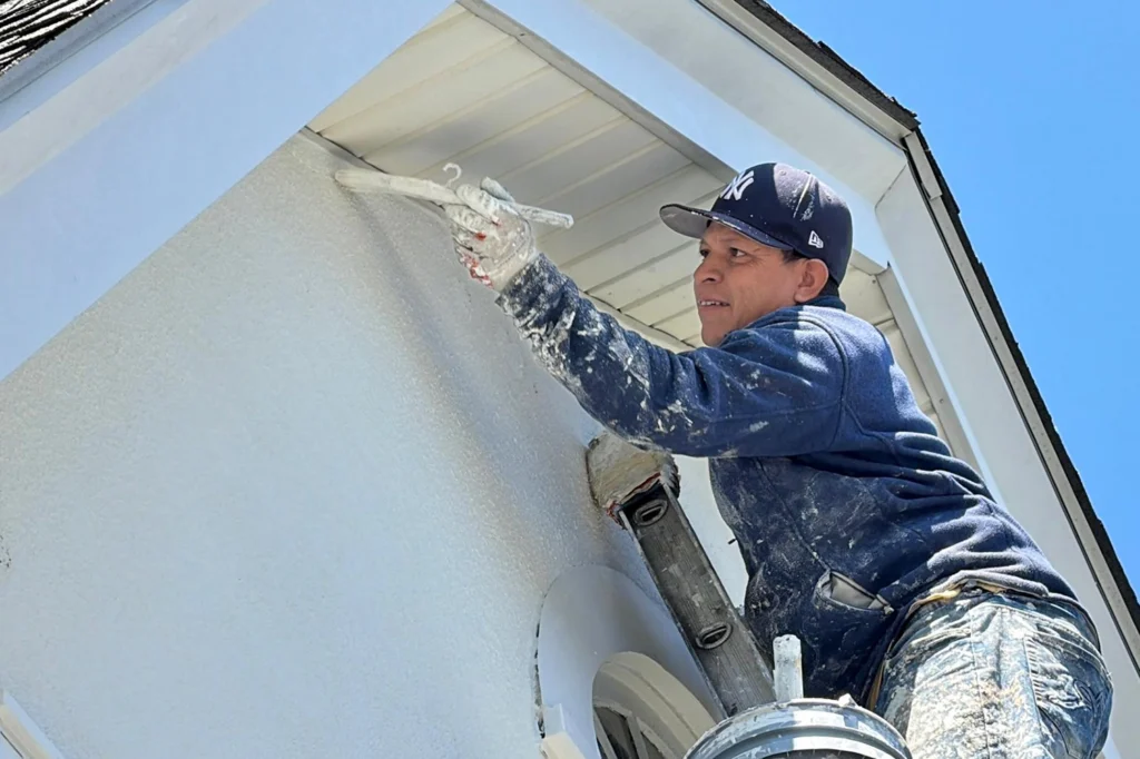 Years of Stucco Wear, Bird Holes, and Staining in Fair Lawn, NJ, Repaired the Right Way 4 ZD Stucco Repair technician applying protective coating after stucco repairs