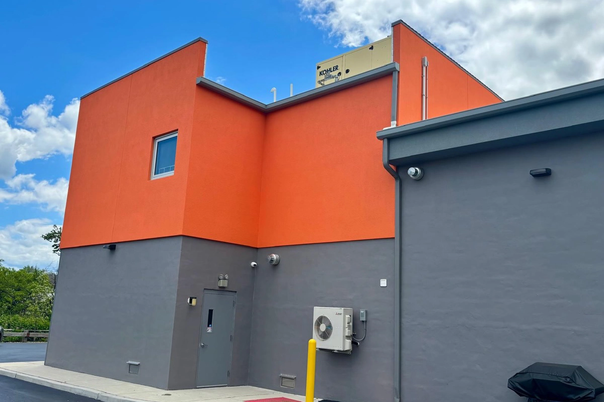 Commercial stucco painting on side wall of Wet Side Car Wash in Port Monmouth, NJ – orange and gray two-tone elastomeric finish by ZD Stucco Repair