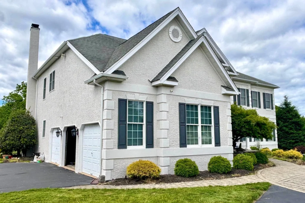 Complete House Stucco Restoration in Flemington, NJ: A Case Study 4 Restored stucco exterior of Flemington home showing repaired garage facade, white stucco finish with protective elastomeric coating, and properly sealed windows preventing water infiltration
