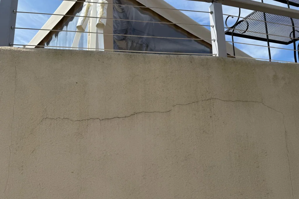 Horizontal crack in stucco wider than 1/8 inch, indicating foundation movement and structural concern