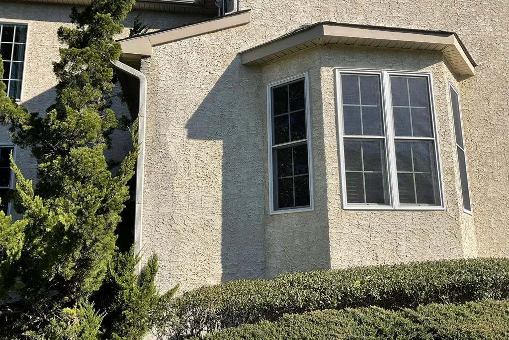 Well-maintained stucco house exterior with bay window in New Jersey — a visually clean facade that still requires a professional pre-purchase stucco inspection to rule out hidden moisture damage