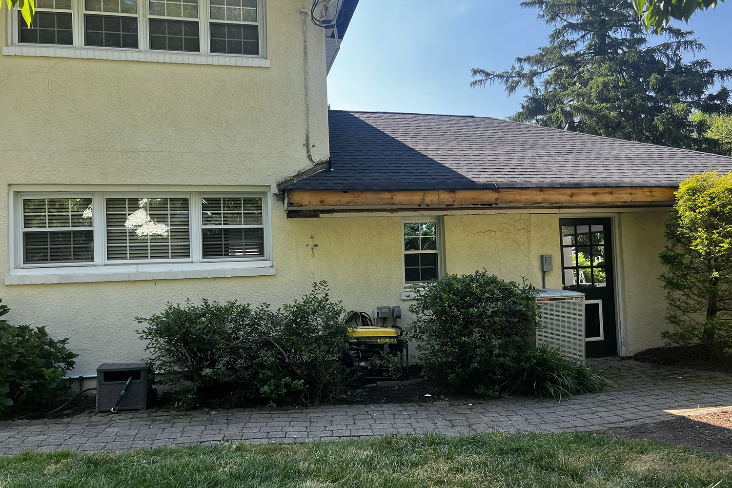 New Jersey stucco house exterior showing multiple cracks, exposed deteriorated fascia boards, and signs of water damage — a typical candidate for pre-purchase stucco inspection