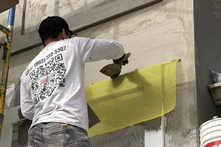 Contractor installing a waterproofing membrane on a stucco wall
