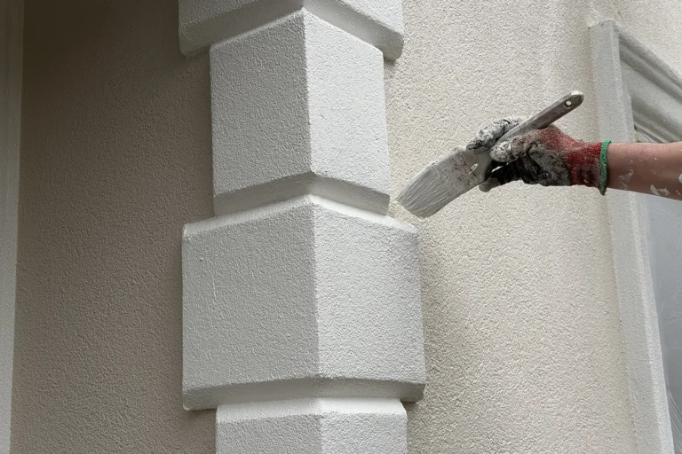 Contractor applying a fresh protective coating to decorative stucco trim to help prevent fading and weather damage.