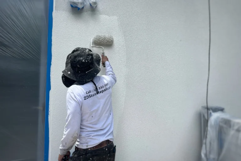 ZD Stucco Repair contractor rolling a fresh protective coating onto an exterior stucco wall