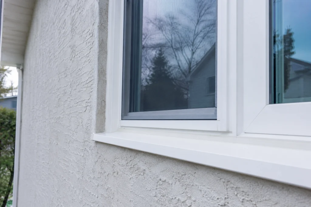 Stucco vs Fiber Cement Siding: 2026 Comparison for New Jersey Homeowners 5 Close-up of a finished stucco wall surrounding a white-framed residential window