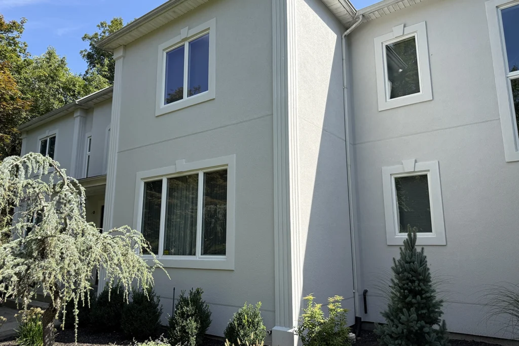 Light-colored residential stucco exterior with a clean and even finish in direct sunlight