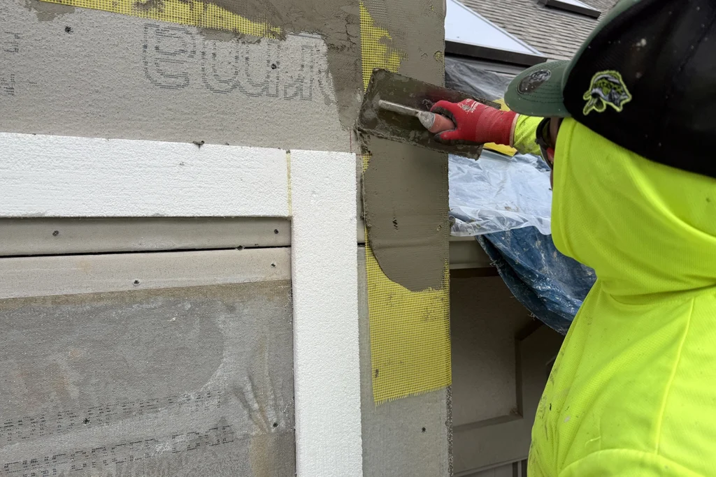Licensed stucco contractor in New Jersey applying base coat over fiberglass mesh during professional EIFS stucco repair — ZD Stucco Repair