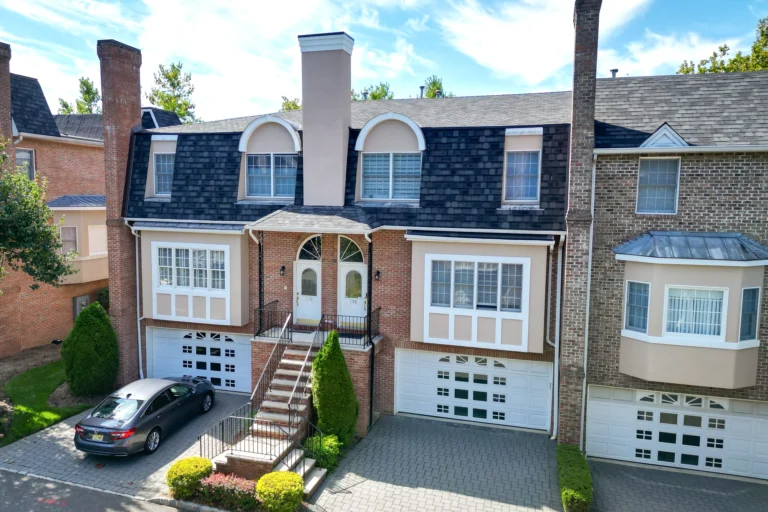 Restored duplex front exterior with brick walls and stucco window surrounds in Cresskill, New Jersey.