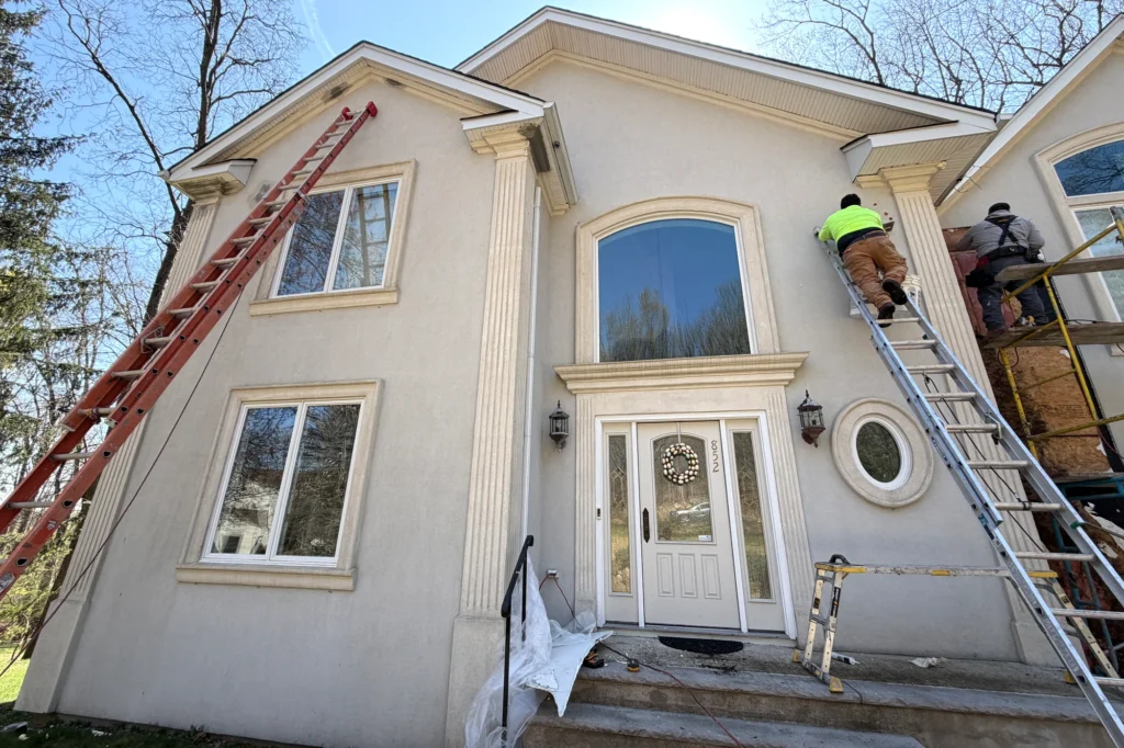 Smooth Stucco Finish: Pros, Cons, Cost & Common Problems 6 Front stucco facade with ladders and scaffolding before restoration in Franklin Lakes