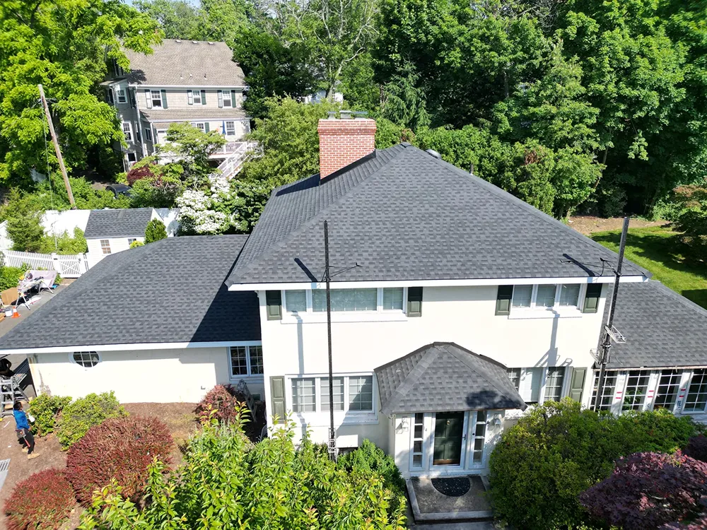 Aerial view of a stucco home with a dark asphalt shingle roof